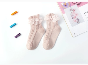 Close-up of pink knit baby socks with mesh ruffle lace trim and hollow out floral patterns
