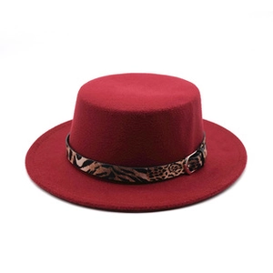 Détail d'un chapeau en feutre rouge avec ruban léopard et boucle dorée élégante