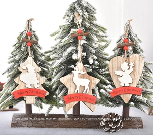 Close-up of wooden Christmas ornaments featuring stars and trees on snowy branches