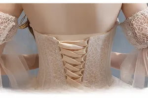 Detailed corset back of a champagne bridal gown with delicate lace and ribbon ties