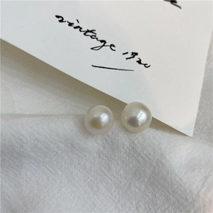 Macro shot of natural white freshwater pearls on textured white fabric with vintage card