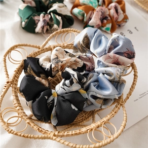 Floral satin scrunchies in assorted colors displayed in a rustic woven basket
