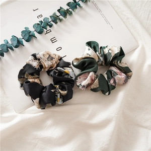 Detailed close-up of floral satin scrunchies in black and dark green on stylish magazine