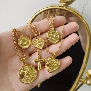 Detail of diverse 18K gold plated stainless steel pendants with angel and coin motifs