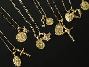 Collection of 18K gold plated titanium steel necklaces with vintage pendants on black background