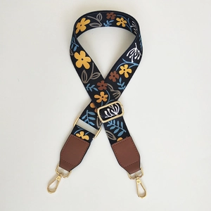 Detail of floral wide shoulder strap with ethnic patterns and gold metal swivel hooks