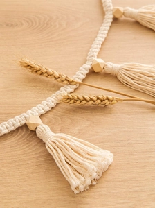 Detail of bohemian cotton fringe wall hanging with wooden beads and wheat accents