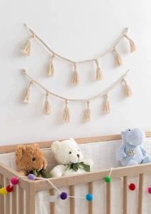 Close-up of beige macrame tassel garland with natural wooden beads for boho nursery wall decor