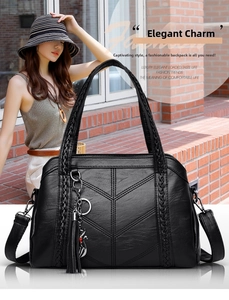 Close-up of black leather tote bag featuring woven handles and a cute cat tassel charm