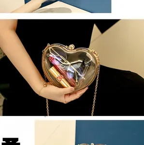 Detail view of heart-shaped acrylic clutch with gold metal frame and long chain strap