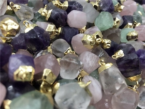 Close-up of mixed raw natural crystal pendants with gold edges and mounting hooks