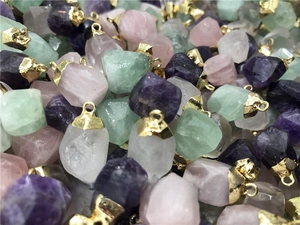 Detailed macro of multi-color natural raw stone pendants with gold plated caps and loops