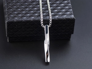 Detail view of twisted bar pendant necklace in silver stainless steel on jewelry box