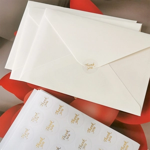 Detail view of gold foil Thank You seal stickers on elegant white envelopes