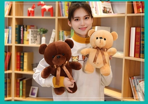 Close-up of brown plush teddy bears with ribbon bows held by a smiling model