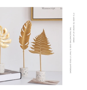 Modern gold metal monstera and fern leaf ornaments with white terrazzo base detail