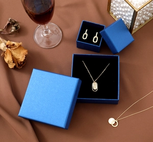Elegant peacock blue jewelry gift box set with gold necklace and earrings on a luxury table