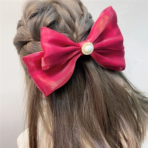 Detail of burgundy satin double bow hair clip featuring a centered pearl and crystal inlay