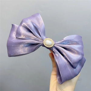 Macro shot of a purple satin double-layered bow hair clip with pearls and rhinestones