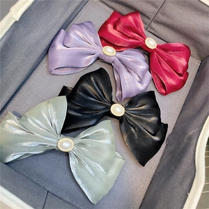 Detail of satin bow hair clips in vibrant colors featuring pearl accents in a tray