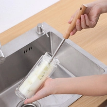 Close-up of long stainless steel handle brush cleaning a deep water jug in the sink