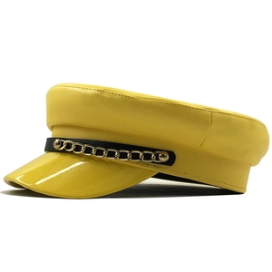 Detail of yellow PU leather military hat featuring black strap and gold chain accent