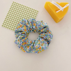 Chouchou à fleurs bleues avec motifs jaunes et orange sur un tissu de couleur crème