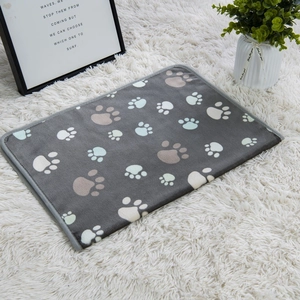 Detailed view of dark grey flannel pet blanket with paw prints on a white plush carpet