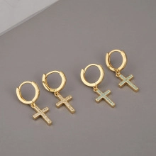 Close-up of gold-plated cross dangle earrings featuring micro-pave cubic zirconia