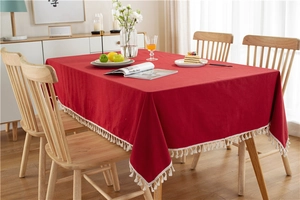 Close-up of red washed cotton tablecloth featuring decorative fringe tassels and fabric texture