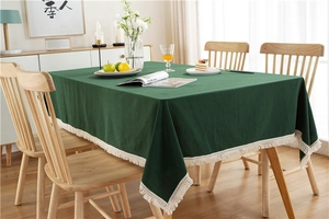 Close-up of dark green cotton tablecloth showing fabric texture and cream fringe trim