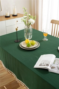 Close-up of deep green washed cotton tablecloth featuring decorative tassel fringe edge