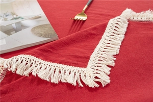 Close-up of red washed cotton tablecloth featuring delicate white fringe tassels