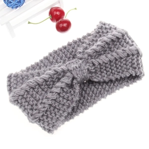 Detail of grey knitted winter headband with chunky cable texture and central bow decoration