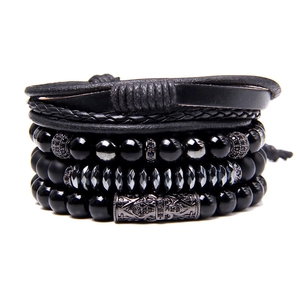 Detail of multi-layered men's bracelet with black beads, woven leather and carved metal