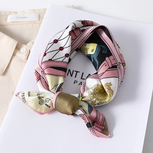 Close-up of silk satin square scarf with crown print tied in a bow on a white board