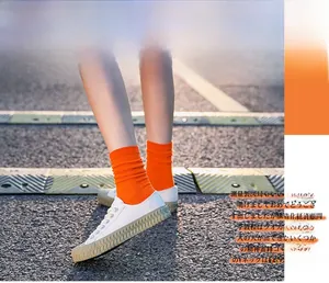 Outdoor close-up of vibrant orange ribbed socks paired with white wavy platform sneakers