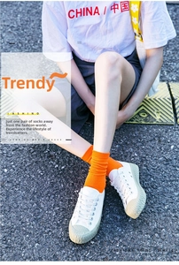 Detail of bright orange ribbed cotton socks paired with white platform canvas sneakers