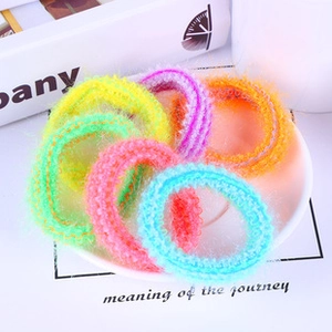 Close-up of vibrant elastic plush hair ties in various colors on a white ceramic plate