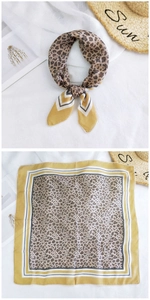 Detailed flat lay of leopard print silk scarf with warm decorative vacation props