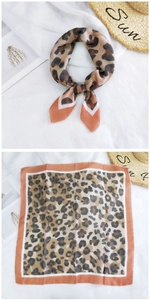 Detail of leopard print neck scarf with orange contrast border and tied styling