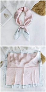 Detailed close-up of a pink geometric silk square scarf with delicate floral borders