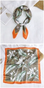 Detail of square silk scarf with green tropical orchid prints and orange border edges