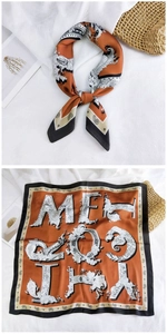 Detail of square silk scarf with orange paisley pattern and black border on straw bag