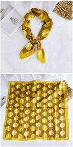 Detail of mustard yellow silk-like scarf with geometric print on white background