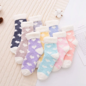 Eight pairs of soft coral fleece heart socks in various colors on a beige knit blanket