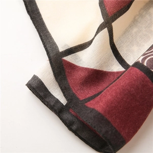 Macro shot of geometric color-block scarf showing fine woven texture and burgundy edges