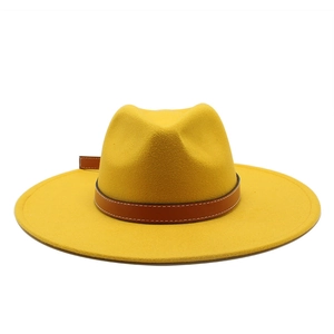 Detailed view of yellow wool fedora hat with brown leather band and white stitching