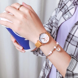Close-up of golden cat dial watch with brown leather strap and beaded bracelet set