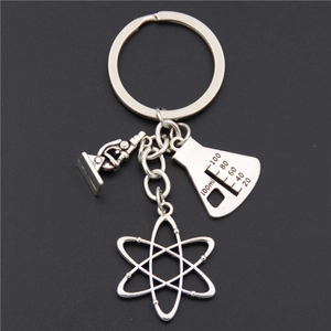 Silver science teacher keychain with microscope, beaker, and atom pendants on dark background
